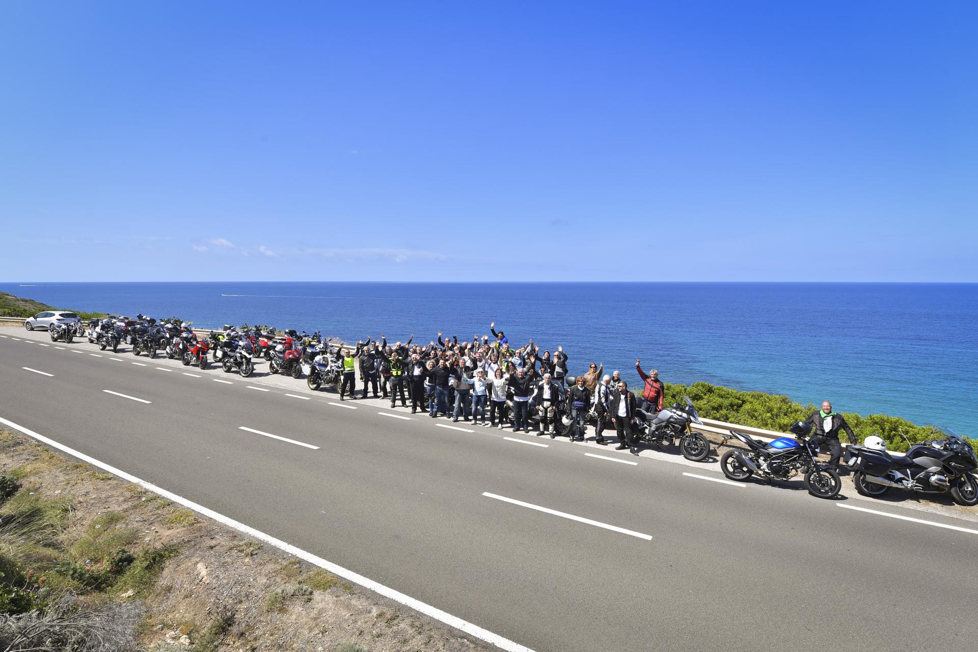 Motociclisti a bordo strada con mare sullo sfondo
